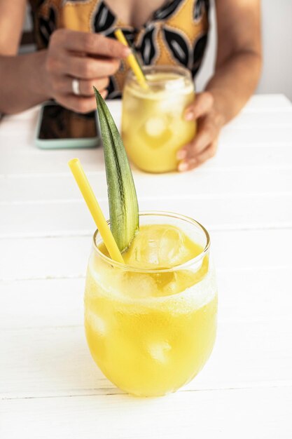 Jus d'ananas fait maison rafraîchissant avec de la glace Fille à une table buvant un jus d'ananas