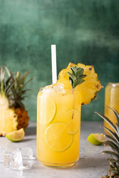 Jus d'ananas fraîchement pressé avec des quartiers de lime et de la glace dans des bocaux en verre