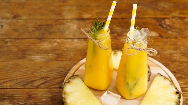 Jus d'ananas frais avec de la glace dans une petite bouteille en verre