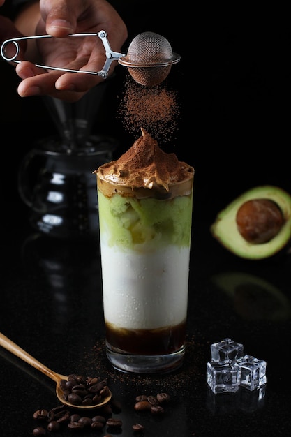 Jus d'avocat frais glacé combiné avec du café dalgona et de la poudre de chocolat saupoudrée