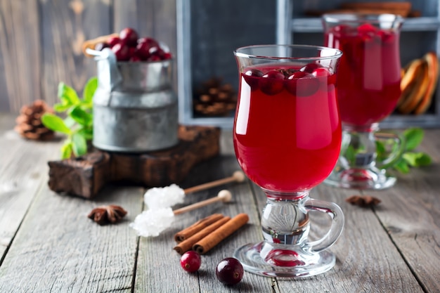 Jus de canneberge frais avec de la cannelle et de l'anis dans des bocaux en verre sur l'ancienne surface en bois. Mise au point sélective.