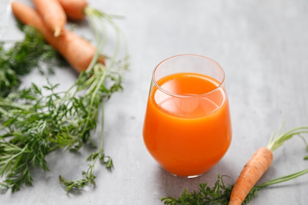Jus de carotte dans un verre et carottes fraîches avec des feuilles