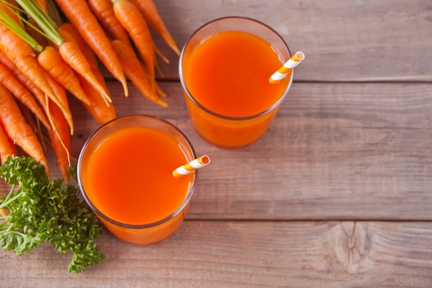 Jus de carotte dans des verres sur fond en bois