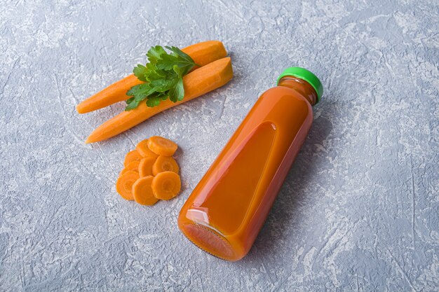 Jus De Carotte Détox Nutritif En Bouteille En Verre. Concept De Régime Alcalin. Boisson Végétarienne Biologique Et Carottes Fraîches Sur Fond Gris