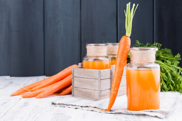 Jus de carotte frais dans un bocal. Carottes fraîches avec des feuilles et boire. Nourriture de printemps pour la santé et la beauté