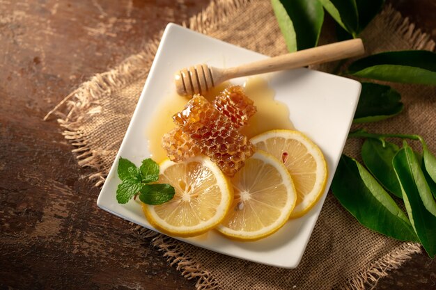 Photo jus de citron avec du miel sur la table en bois, des citrons et des feuilles de sauge.