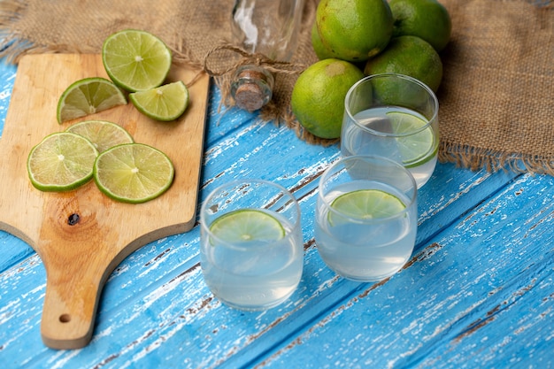 Jus de citron vert et citron sur une table en bois bleue