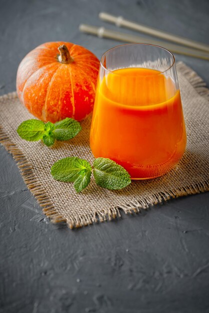 Jus de citrouille frais dans une tasse en verre et des citrouilles orange Concept de nourriture saine et savoureuse Récolte d'automne Espace de copie minimalisme orientation verticale