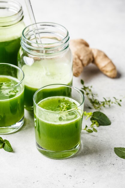 Jus de désintoxication vert au gingembre et à la menthe dans des verres et des bocaux