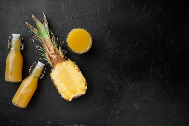 Jus frais d'ananas en verre, sur fond de table en pierre noire noire, vue de dessus à plat, avec espace de copie pour le texte