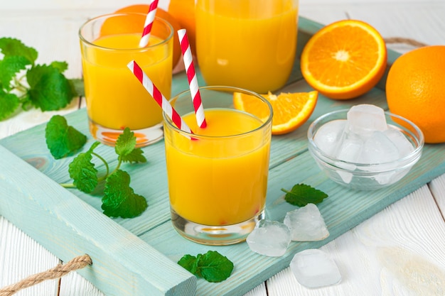 Jus de fruits frais et oranges à la menthe et glaçons sur un bureau léger.