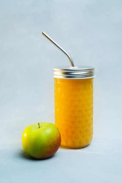 Jus de fruits frais en verre et pomme sur fond gris