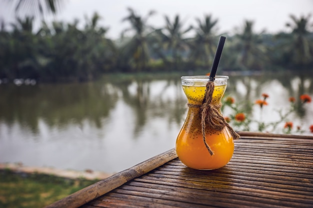 Photo jus de fruits tropicaux jaunes dans un beau verre sur fond de cocotiers.