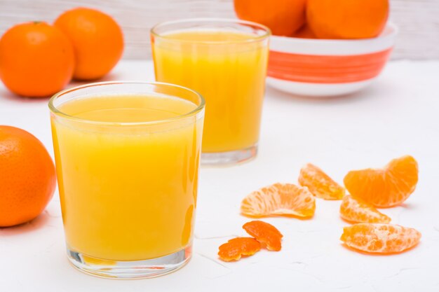 Jus de mandarine dans un verre et tranches de mandarines sur une table