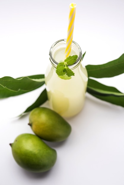 Jus de mangue OU Aam Panna ou Panha dans un verre transparent avec des fruits verts entiers, mise au point sélective