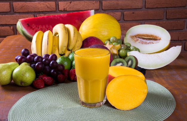 jus de mangue frais avec des fruits en arrière-plan.