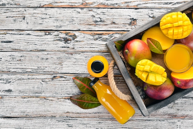 Jus de mangue et de mangue Sur un fond en bois blanc Fruits tropicaux Vue de dessus Espace de copie gratuit