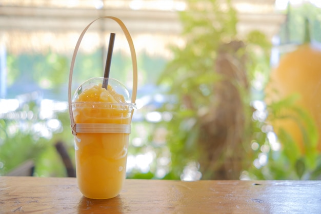 Photo jus de mangue avec paille noire sur table en bois