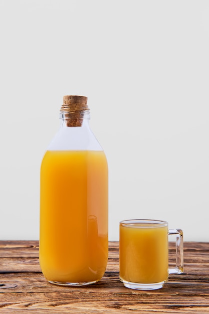 Jus d'orange en bouteille et tasse sur une table en bois