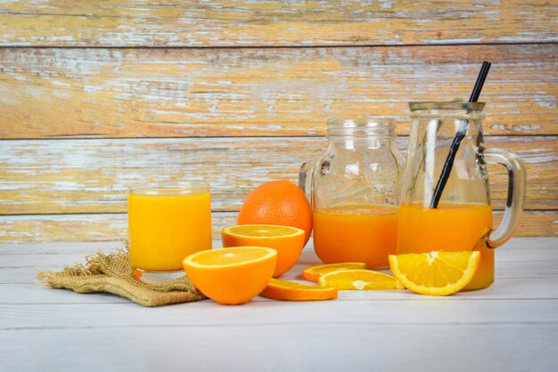 Jus d'orange dans le bocal en verre et une tranche de fruit orange fraîche sur une table en bois, Jus de verre nature morte sur bois