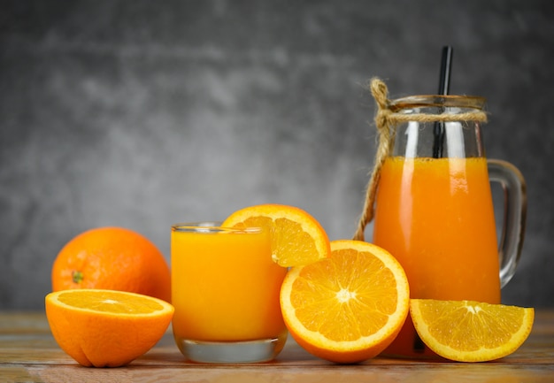 Jus d'orange dans le bocal en verre et une tranche de fruit orange fraîche sur une table en bois