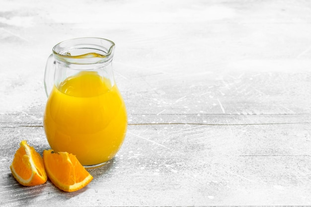 Jus d'orange dans le pichet et tranches d'oranges fraîches