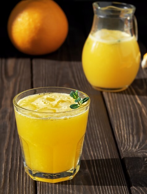 Jus d'orange dans le verre avec des feuilles de menthe et dans un pot