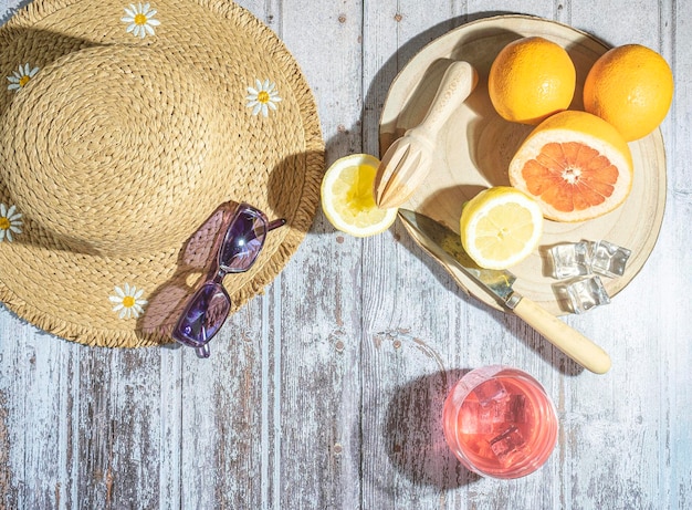 Jus d'orange dans des verres avec chapeau de paille de glace et lunettes de soleil sur table blanche concept de vacances