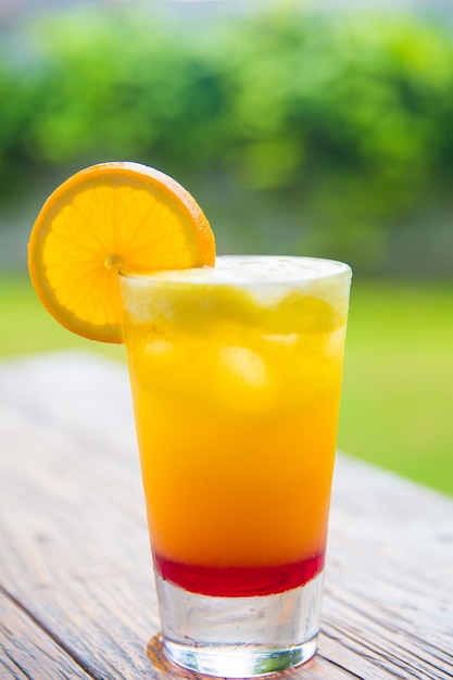 Jus d'orange frais dans le bocal en verre sur un bureau en bois avec fond nature. Notion de vacances.