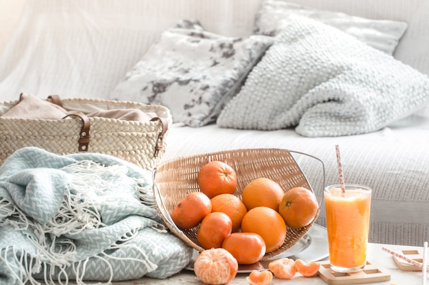 Jus d'orange frais fraîchement cultivé à l'intérieur de la maison, avec une couverture turquoise et une corbeille de fruits