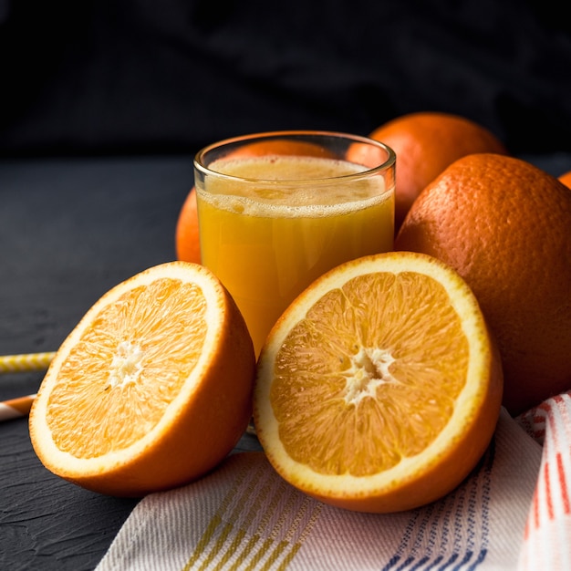Jus d'orange frais et oranges de fruits frais sur une surface noire