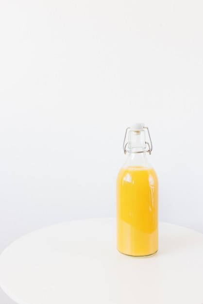 Jus d'orange frais pressé en bouteille avec bouchon sur fond blanc de table Boisson saine