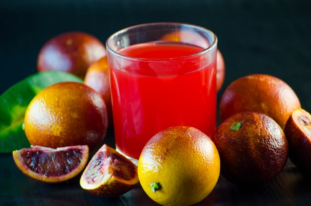 Jus de l'orange sicilienne et fruits frais sur fond noir