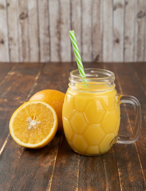 Jus d'orange avec des tranches d'orange sur une table en bois.