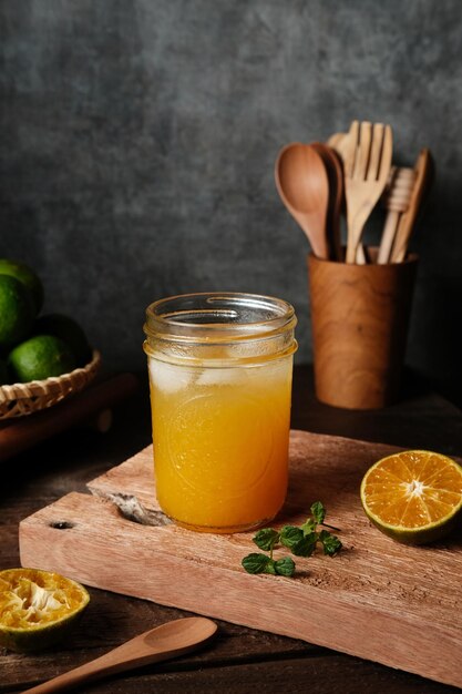 Jus d'orange en verre avec menthe et fruits frais sur planche de bois Selective focus