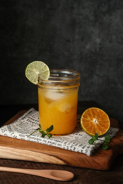 Jus d'orange en verre avec menthe et fruits frais sur planche de bois Selective focus