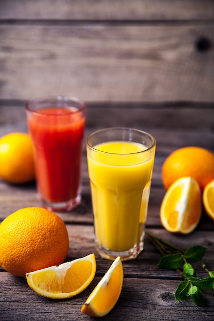 Jus d'orange en verre à la menthe, fruits frais sur table en bois