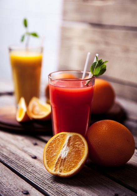 Jus d'orange en verre à la menthe, fruits frais sur table en bois