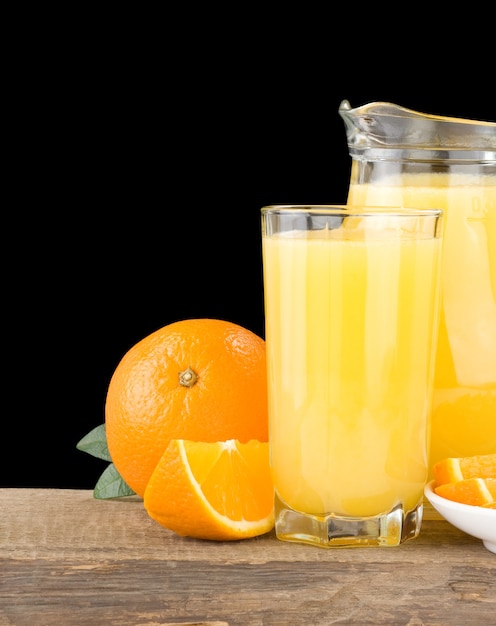 Photo jus d'orange en verre et pichet isolé sur surface noire