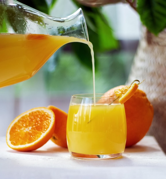 Jus d'orange versé du pichet dans le verre Boisson aux agrumes sains Concept de fraîcheur d'été