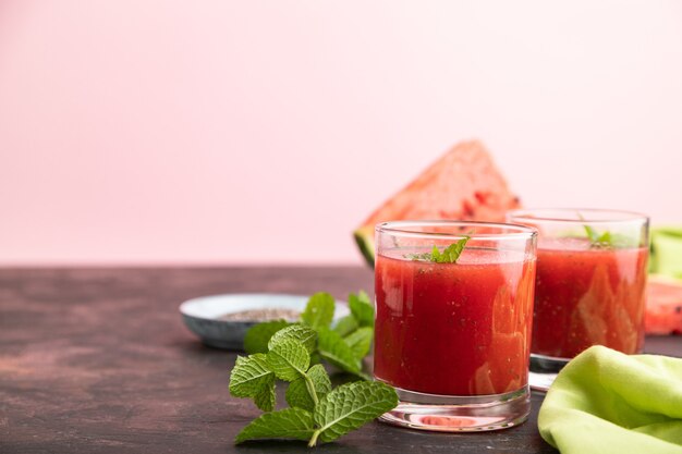 Jus de pastèque aux graines de chia et menthe en verre sur fond noir et rose avec textile vert. Concept de boisson saine. Vue latérale, gros plan, mise au point sélective, espace de copie.