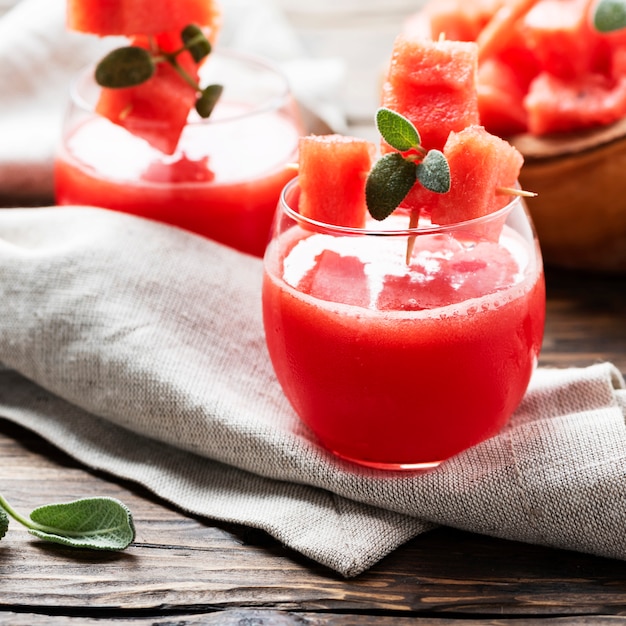 Jus de pastèque froid avec sauge sur la table en bois, mise au point sélective et image carrée