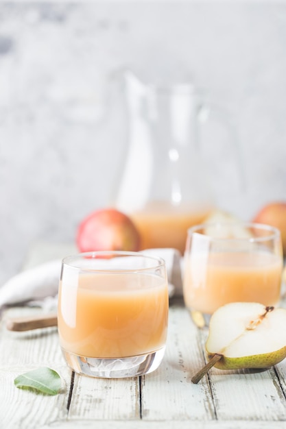 Jus de poire frais dans des verres avec des fruits frais sur fond clair