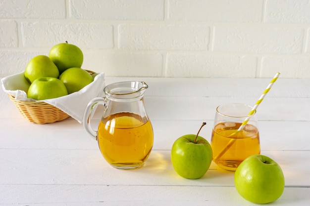 Jus de pomme frais fait maison et pommes vertes sur tableau blanc. Boisson matinale saine.