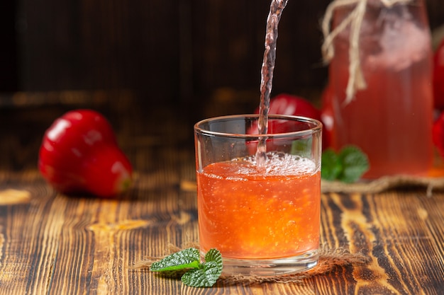 Jus de pomme rose sur une surface en bois sombre