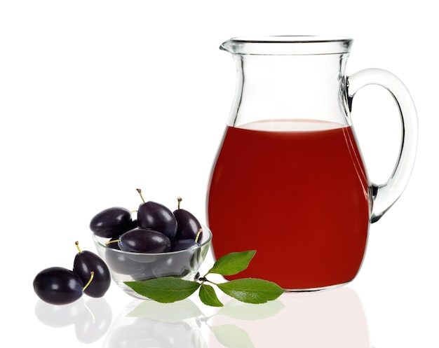 Jus de prune dans une carafe avec des prunes sur fond blanc