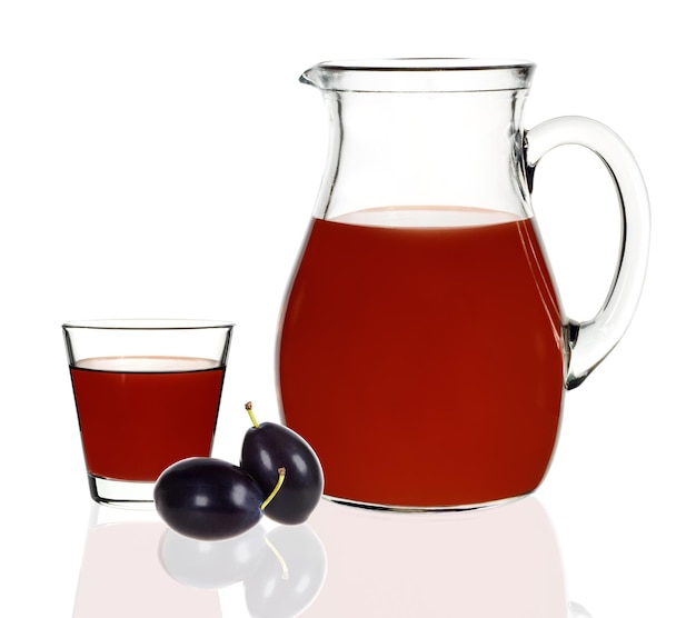 Jus de prune dans un verre et une carafe avec des prunes sur fond blanc