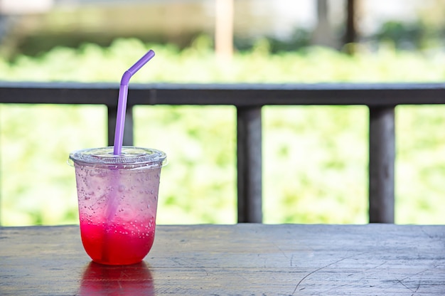 Jus rouge avec de la glace dans un verre en plastique sur la table