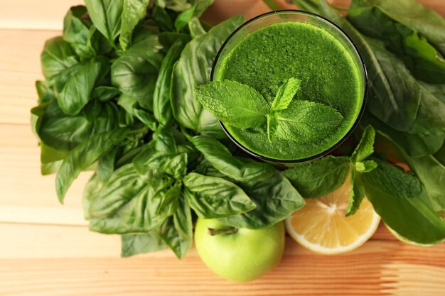 Jus sain vert avec des fruits et des herbes sur une table en bois se bouchent