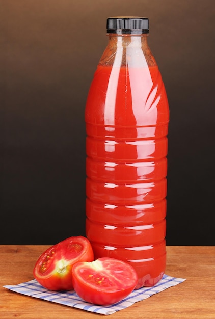 Jus de tomate en bouteille sur table en bois sur fond marron